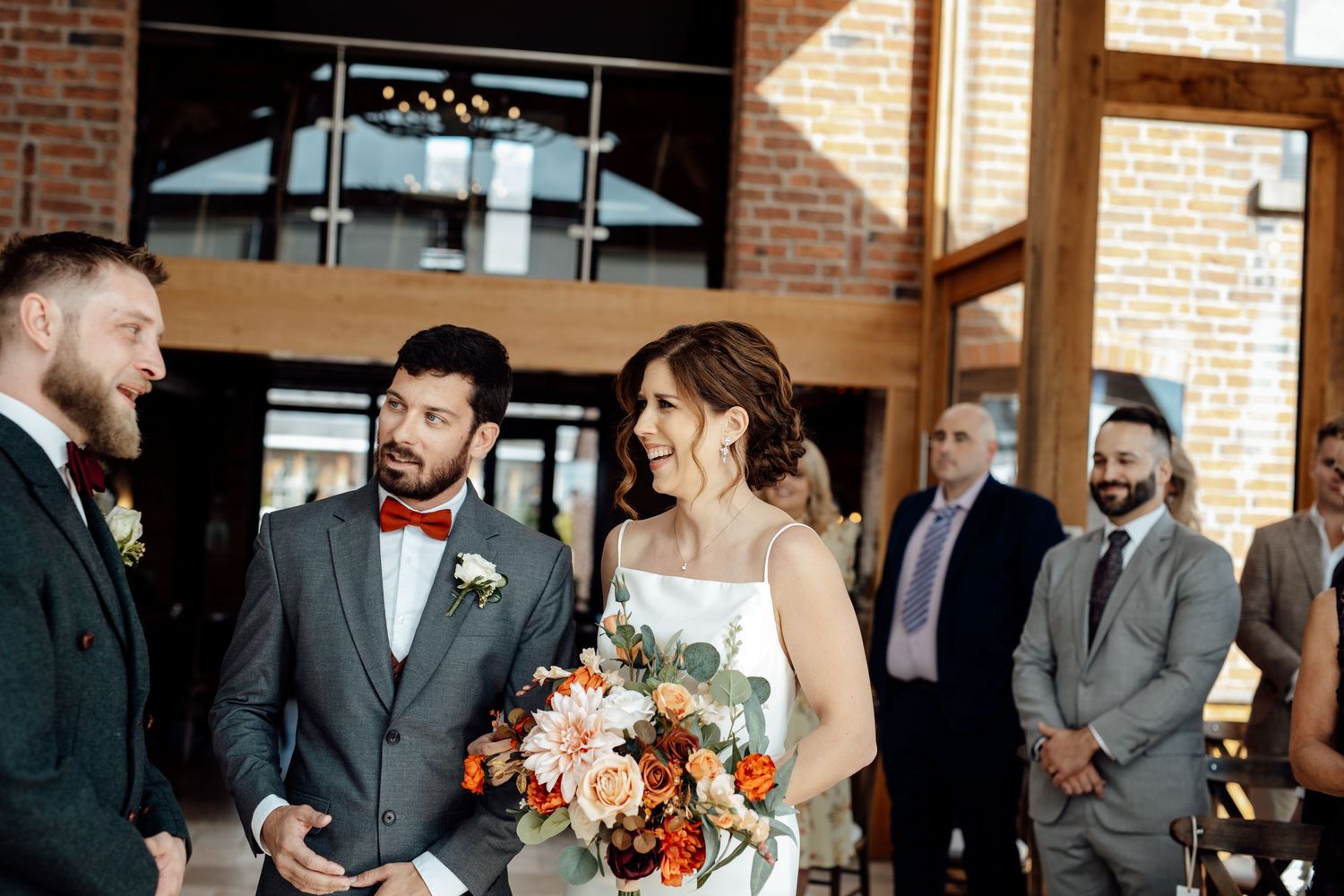 Wedding celebration in a brick-walled venue with natural light streaming through windows.