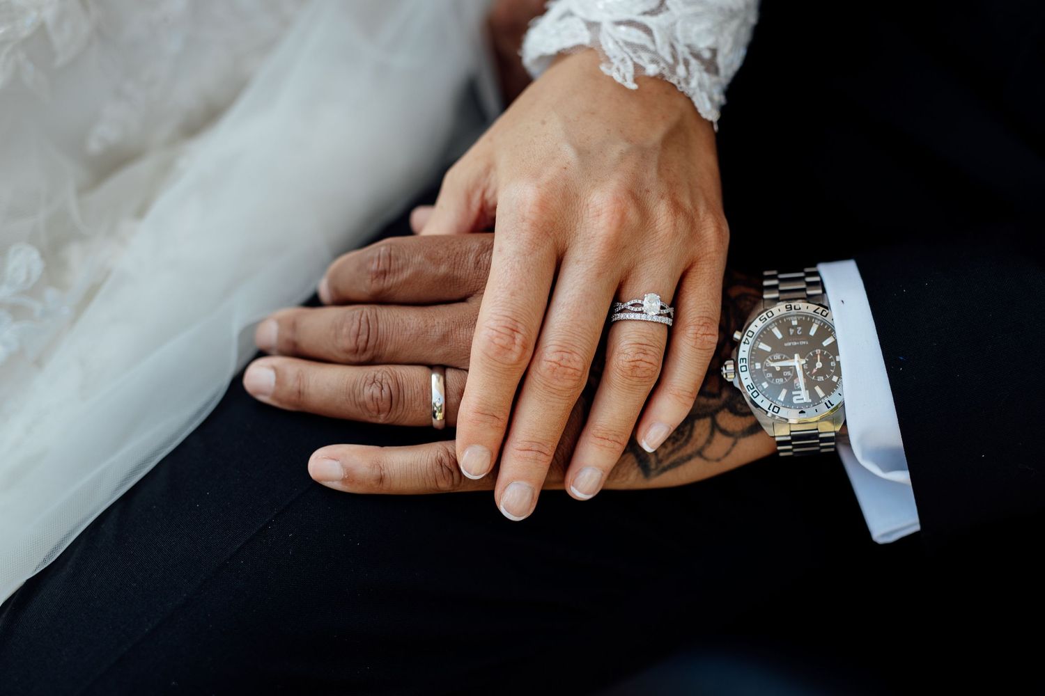Close-up details of wedding rings and hands against a dark background.