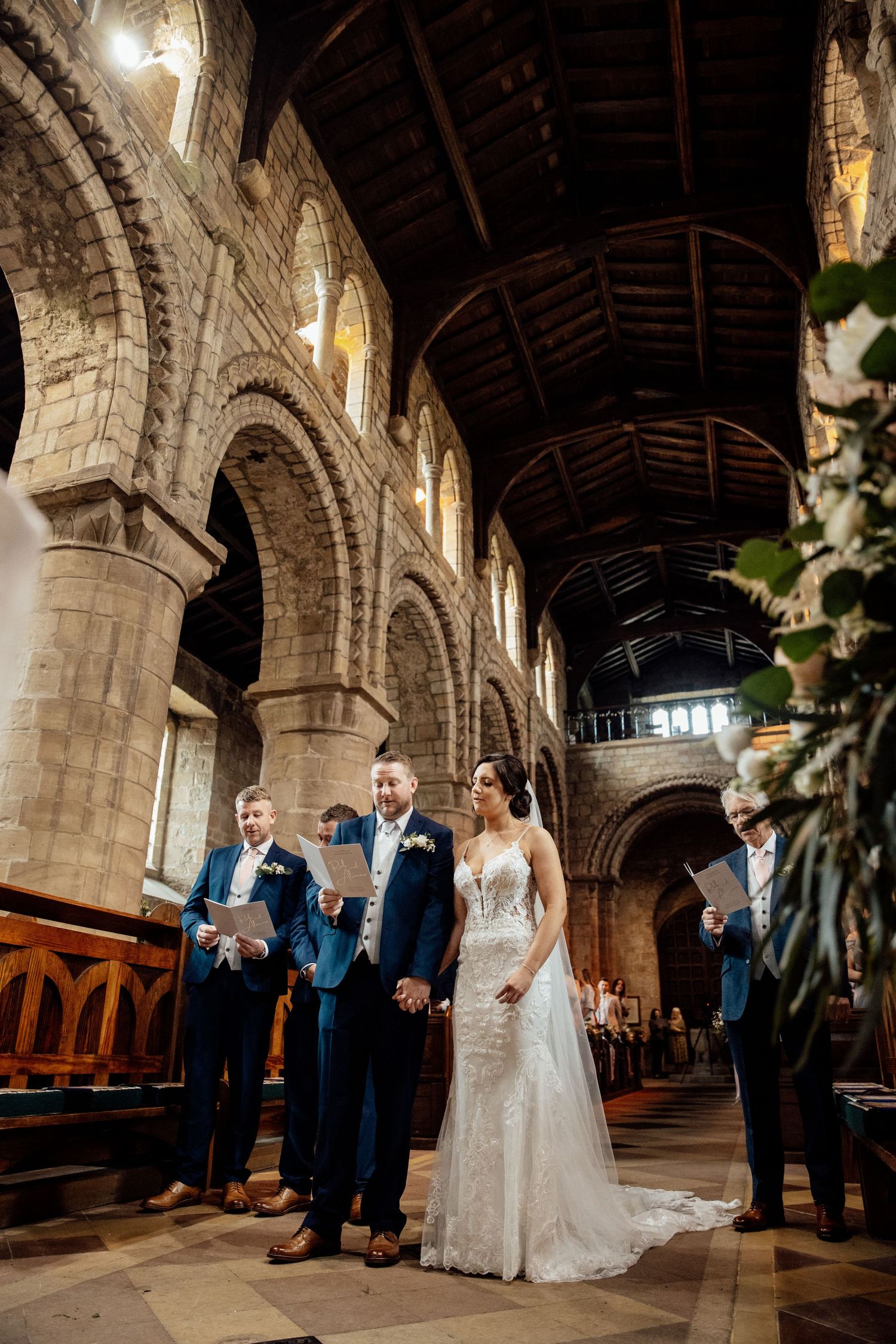 Wedding ceremony taking place inside a grand historic church with beautiful stone arches and high ceilings.