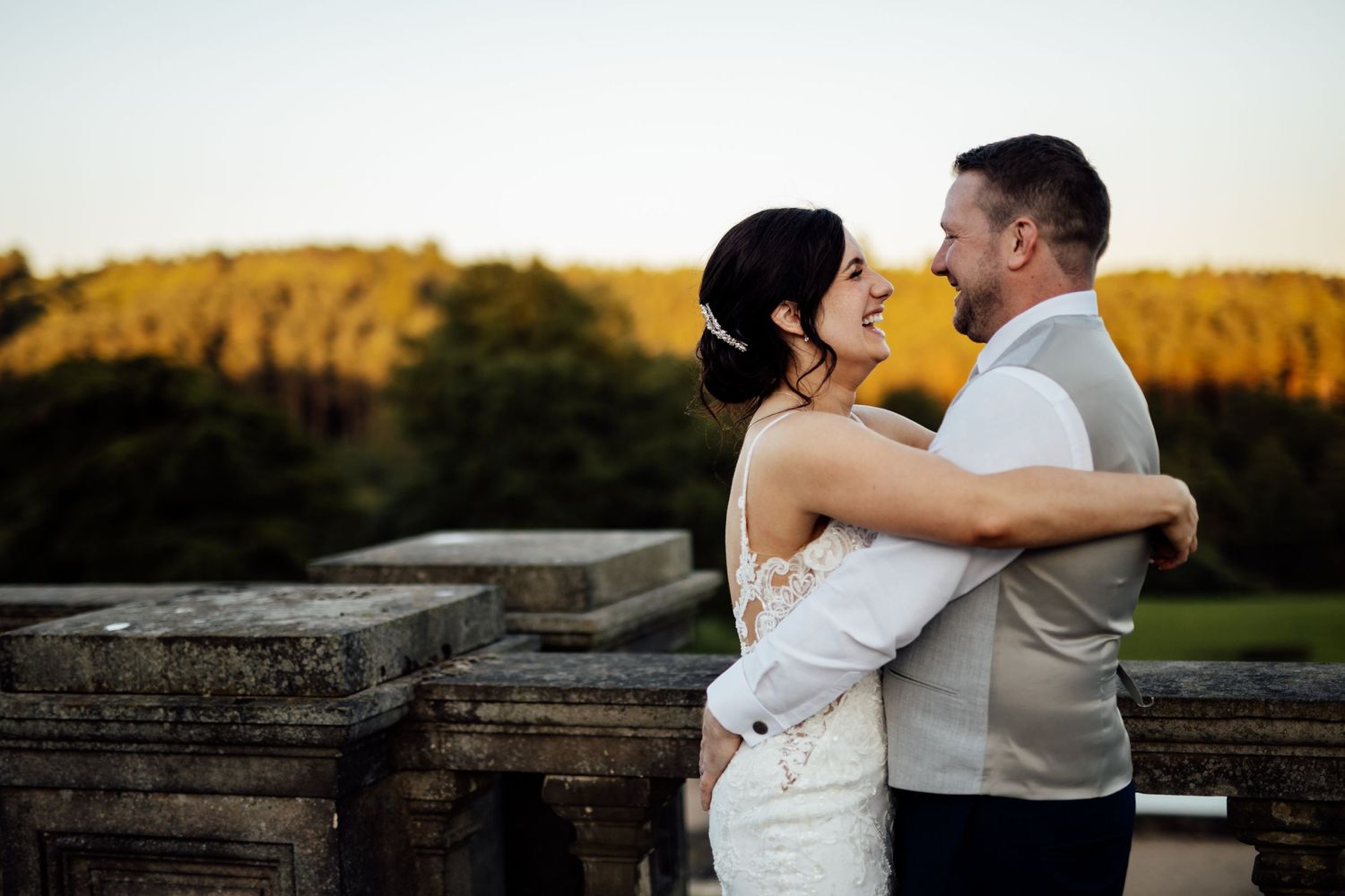 Romantic sunset wedding portraits on a stone wall with warm golden light.