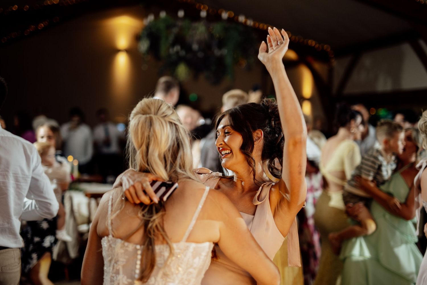 Guests dance and celebrate joyfully on the dance floor at a lively wedding reception.