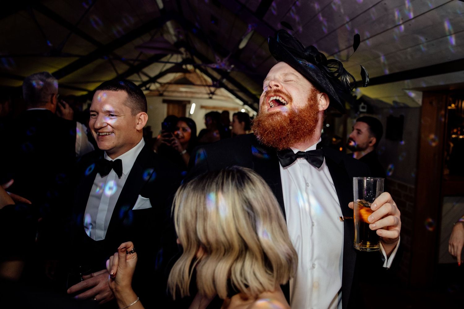 Guests enjoying themselves on a dance floor with purple mood lighting at a wedding celebration.
