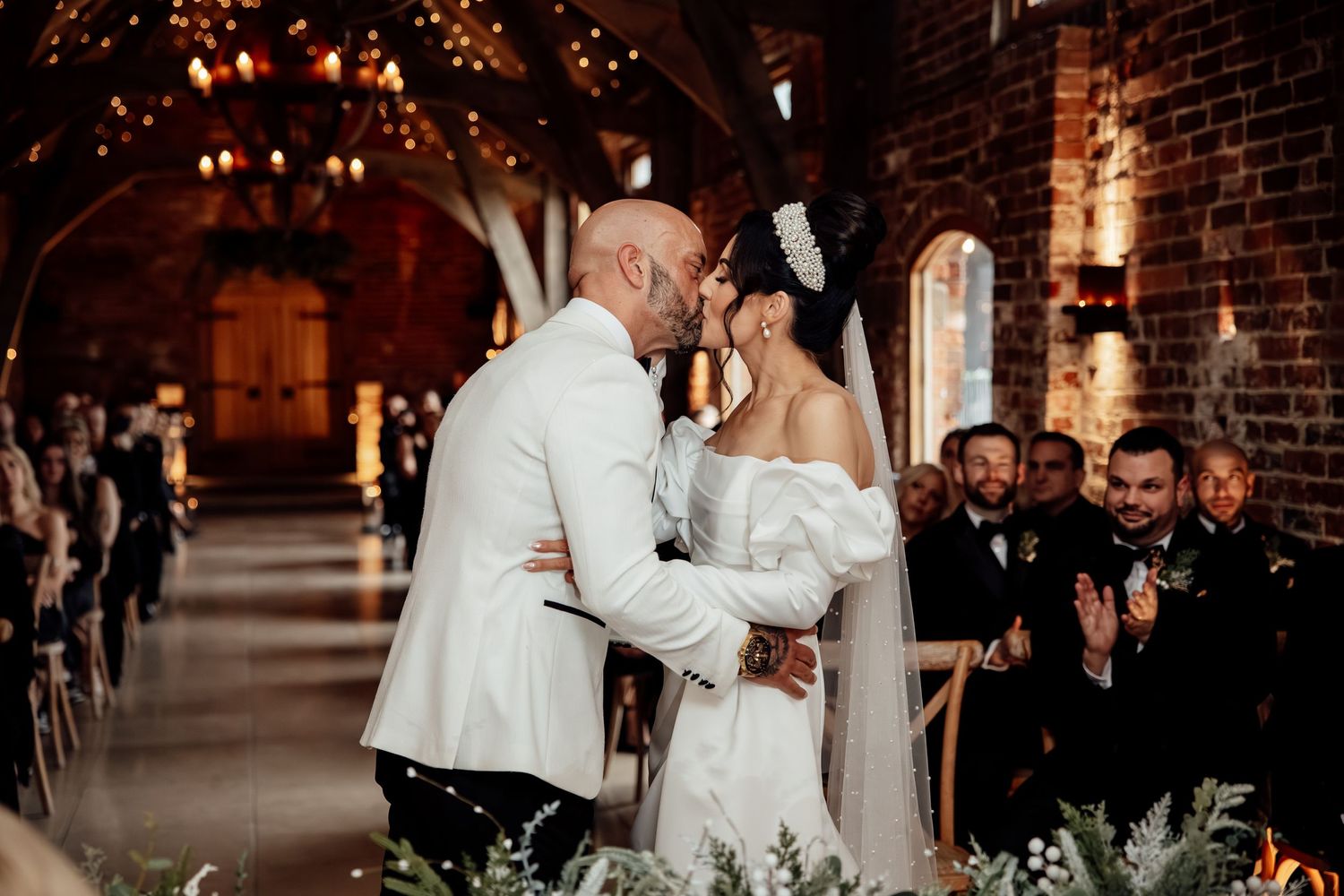 Couple sharing their first dance in a beautifully lit brick venue with guests watching.