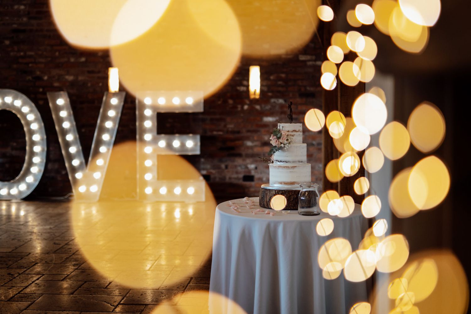 Decorative LOVE sign with bokeh lights and wedding reception table setting.