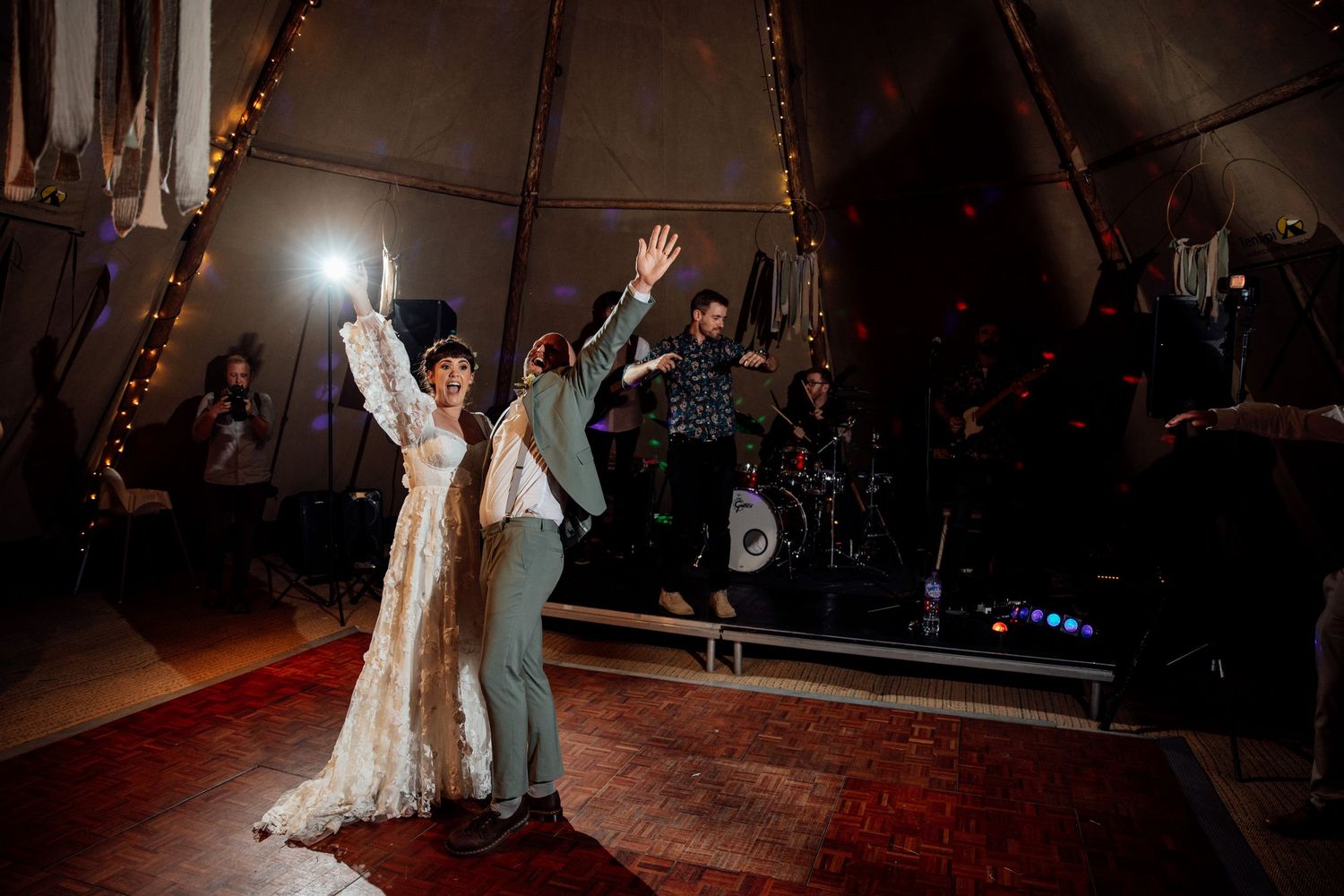 Wedding celebration in a dimly lit tent venue with string lights creating a romantic atmosphere.