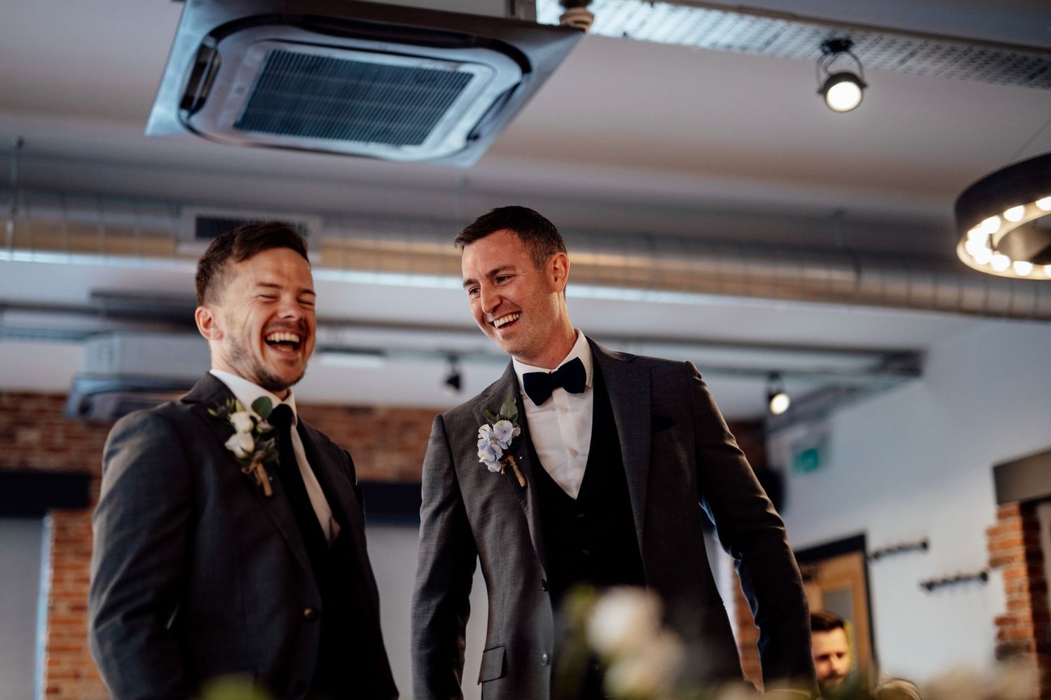 Wedding party sharing laughs during an indoor reception with industrial decor.