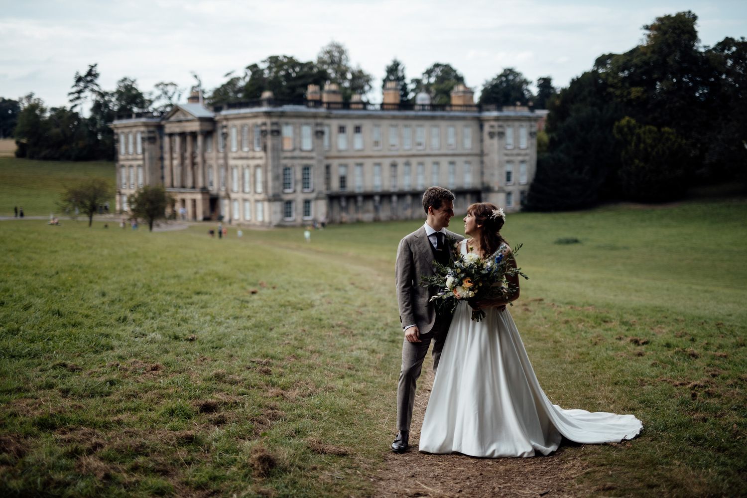 Elegant outdoor wedding venue with historic mansion and sprawling green lawn in background.
