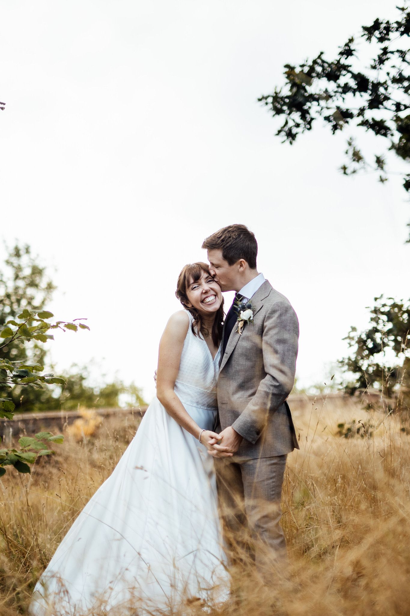 Romantic wedding portraits in a golden field with tall grass during sunset.