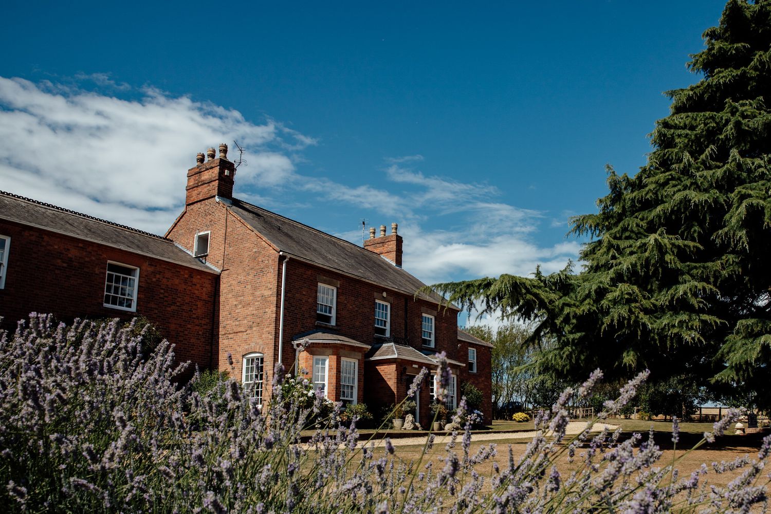 Red brick buildings and landscaped gardens under a bright blue summer sky.