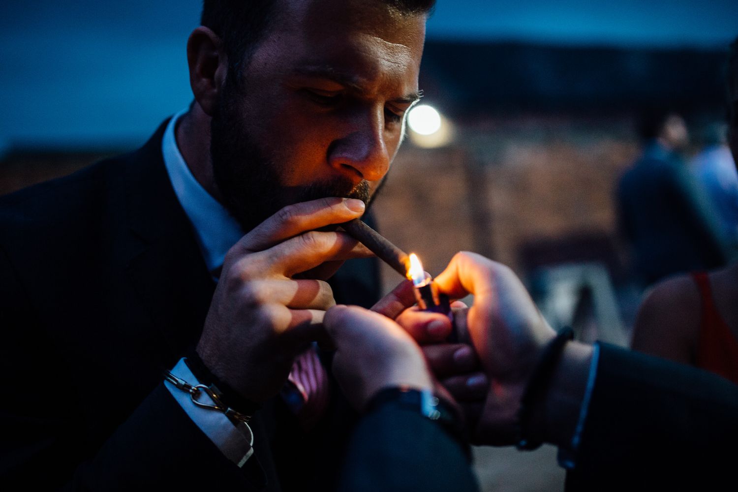 Guest in formal attire lighting a cigarette in the evening.