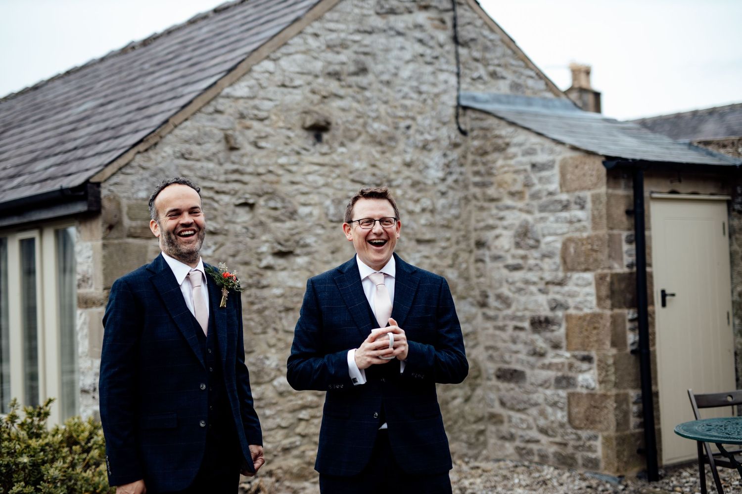 Wedding guests gather outside a charming stone building for celebrations.