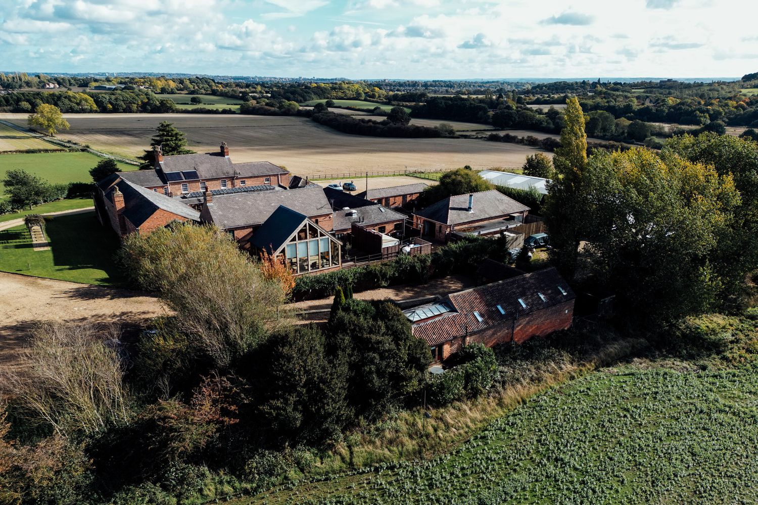 Aerial view of rustic barn venue complex surrounded by green countryside.