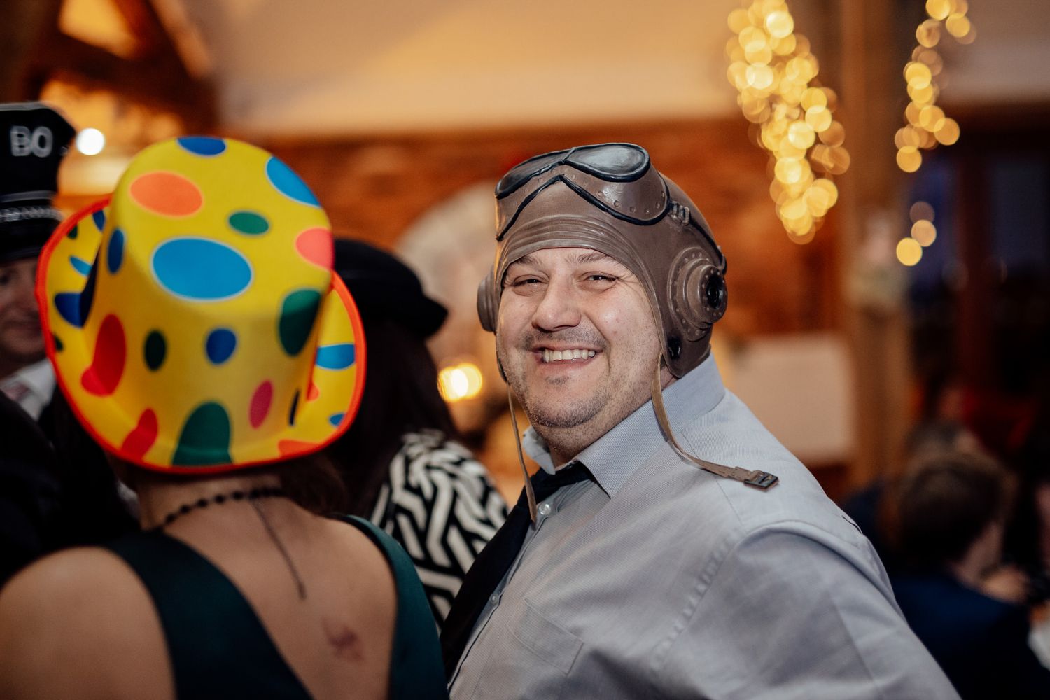 Wedding guests having fun wearing colorful polka dot party hats at a reception.