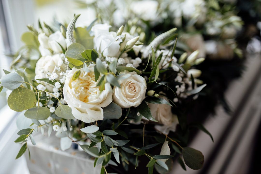 Elegant white rose and greenery wedding bouquet arrangement with delicate floral details.