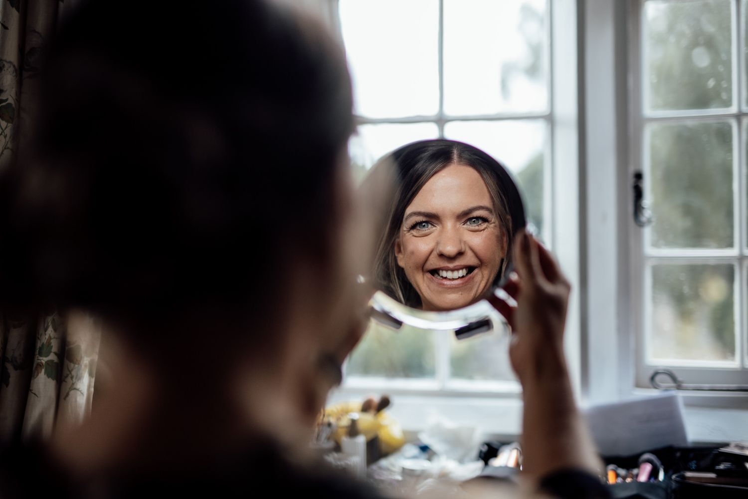 Joyful moments captured through windows during wedding preparations.