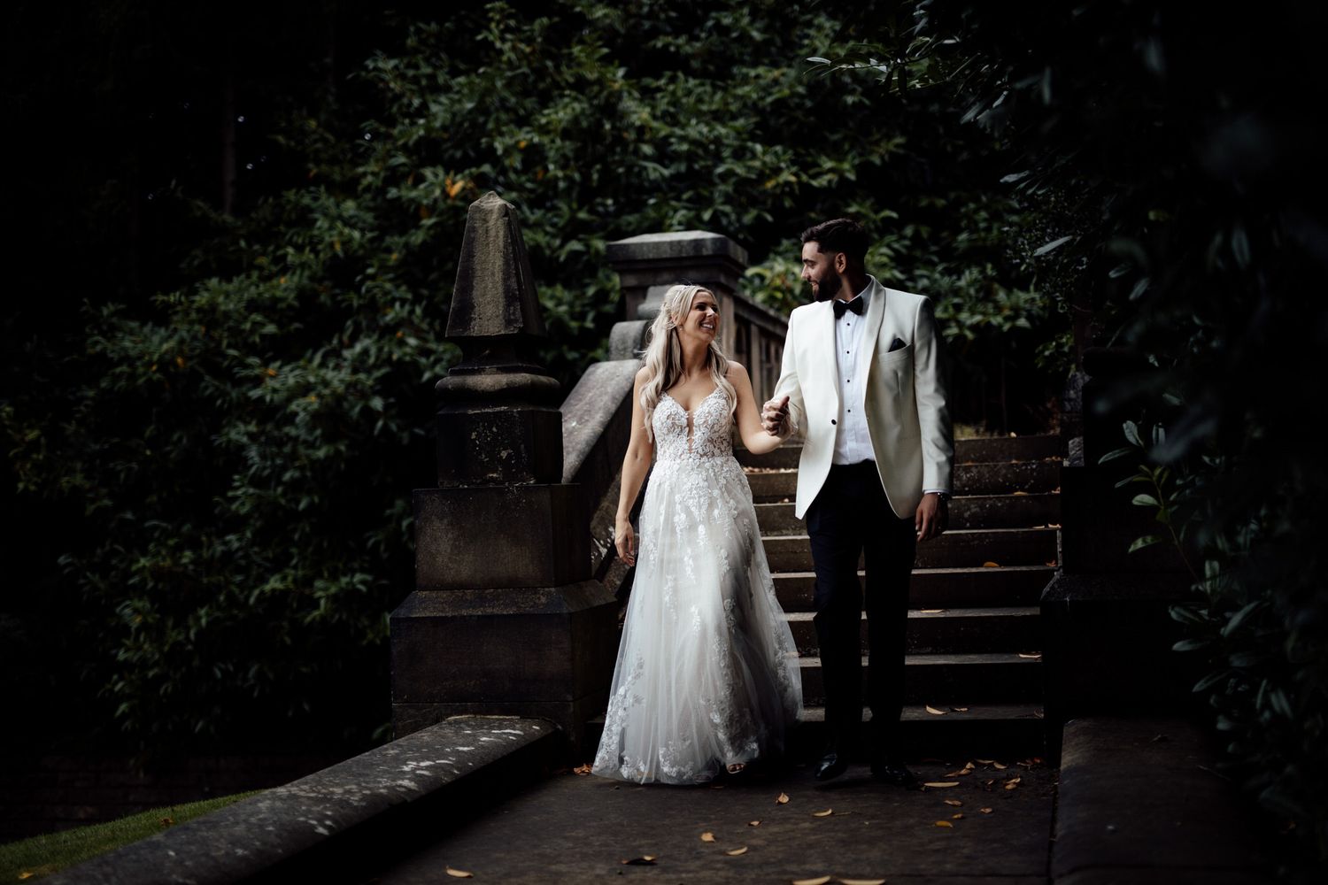Romantic garden pathway surrounded by lush greenery and shadows.