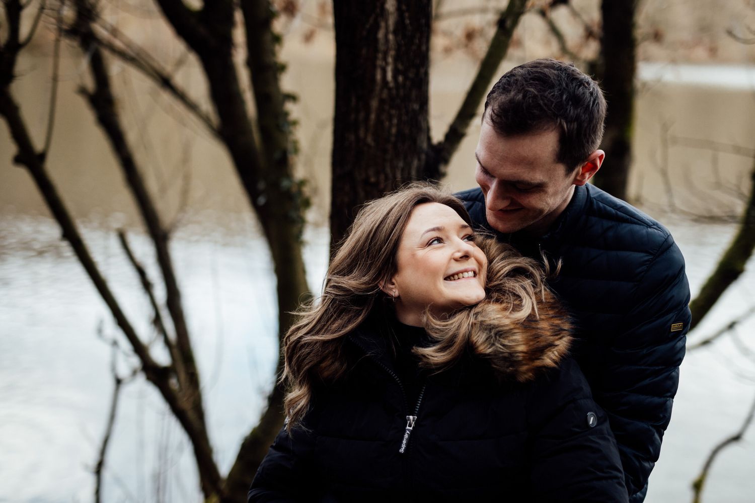 Tender moment between couple in winter coats against snowy background.