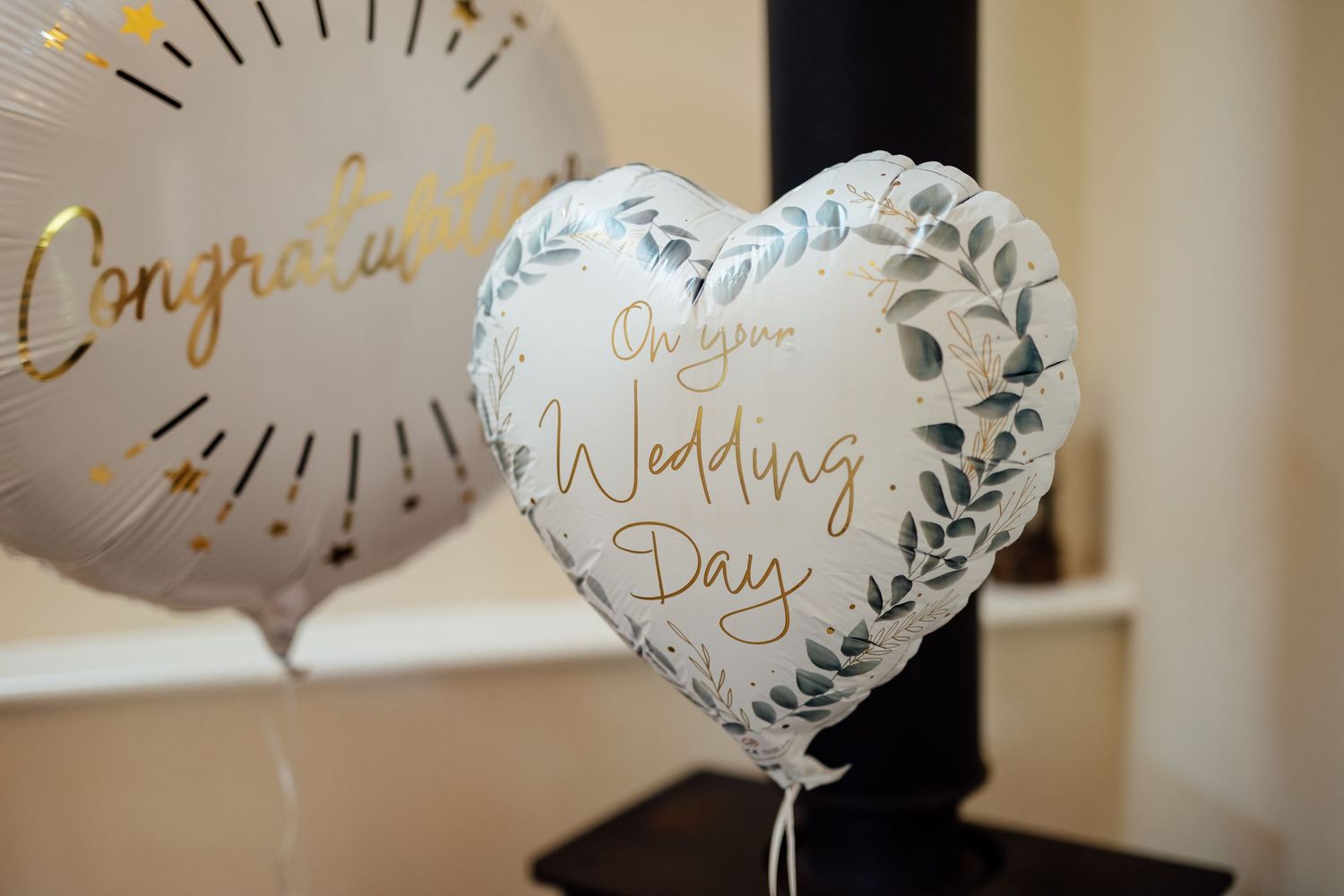 Elegant white and gold wedding day balloons with decorative text.