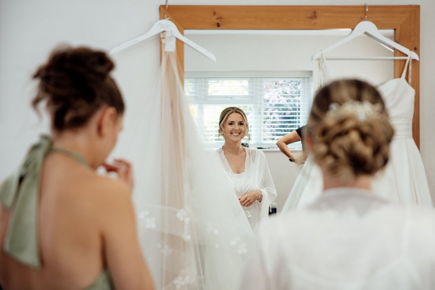 Wedding dresses hanging on white hangers in preparation room.