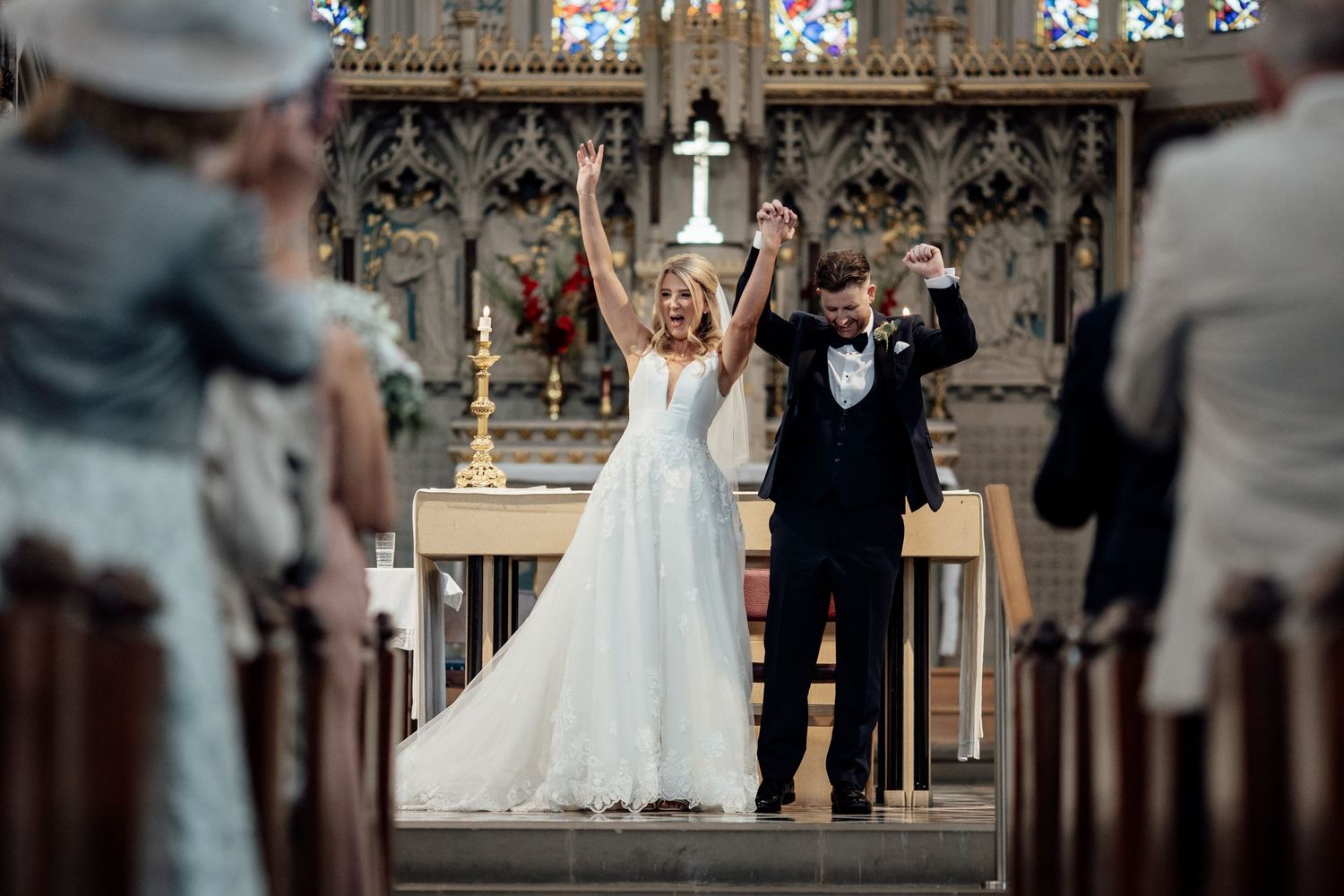 Gothic church interior with ornate stained glass windows and decorative patterns during wedding ceremony.