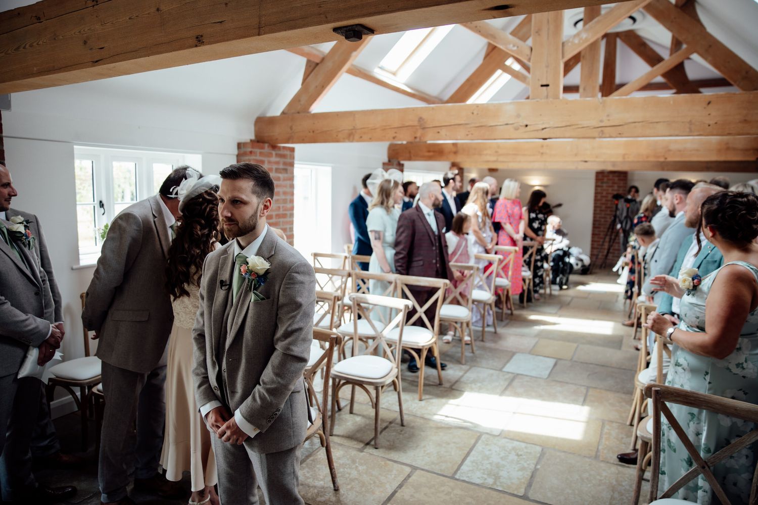 Wedding ceremony setup in a rustic indoor venue with wooden beams and natural light.