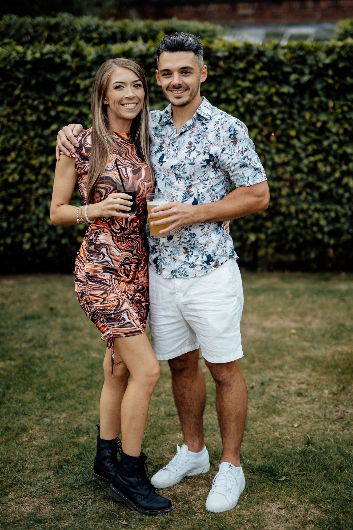 Couple in matching floral outfits posing in garden setting.