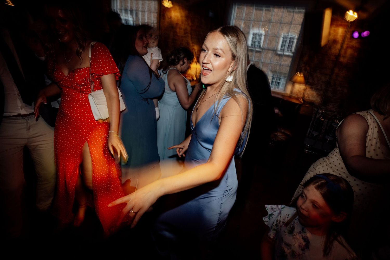 Wedding reception dance party with colorful lighting and guests dancing.