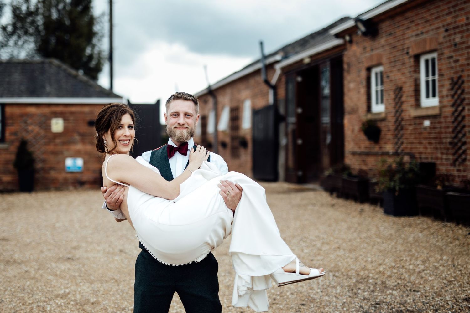 Outdoor wedding venue with rustic brick buildings and gravel pathways.