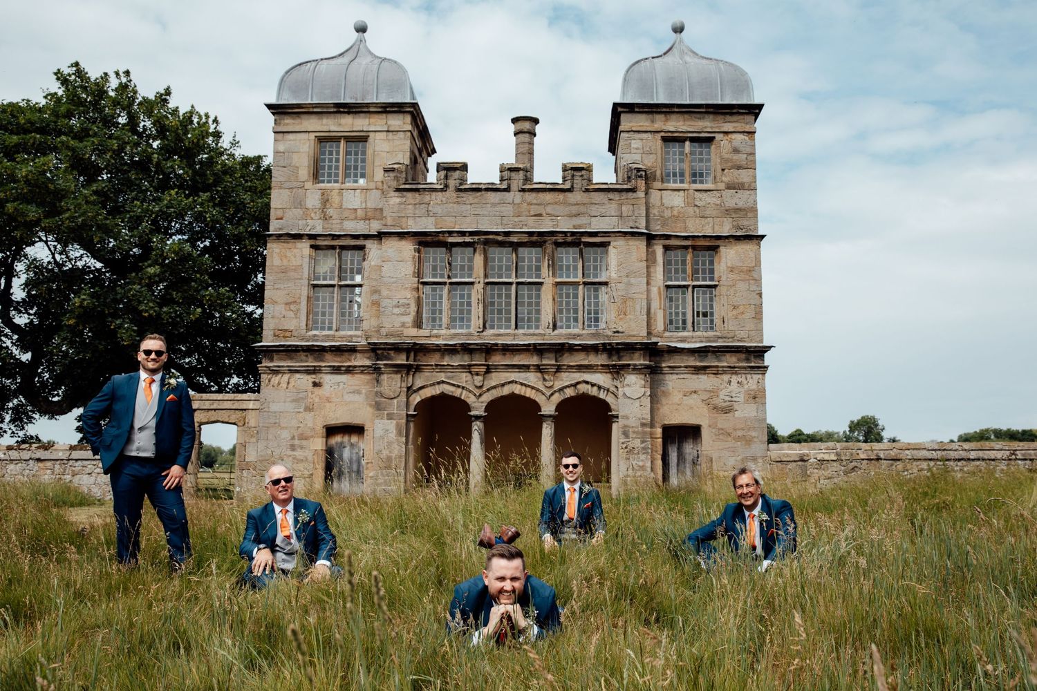 Wedding party posed in front of historic stone mansion with twin towers.