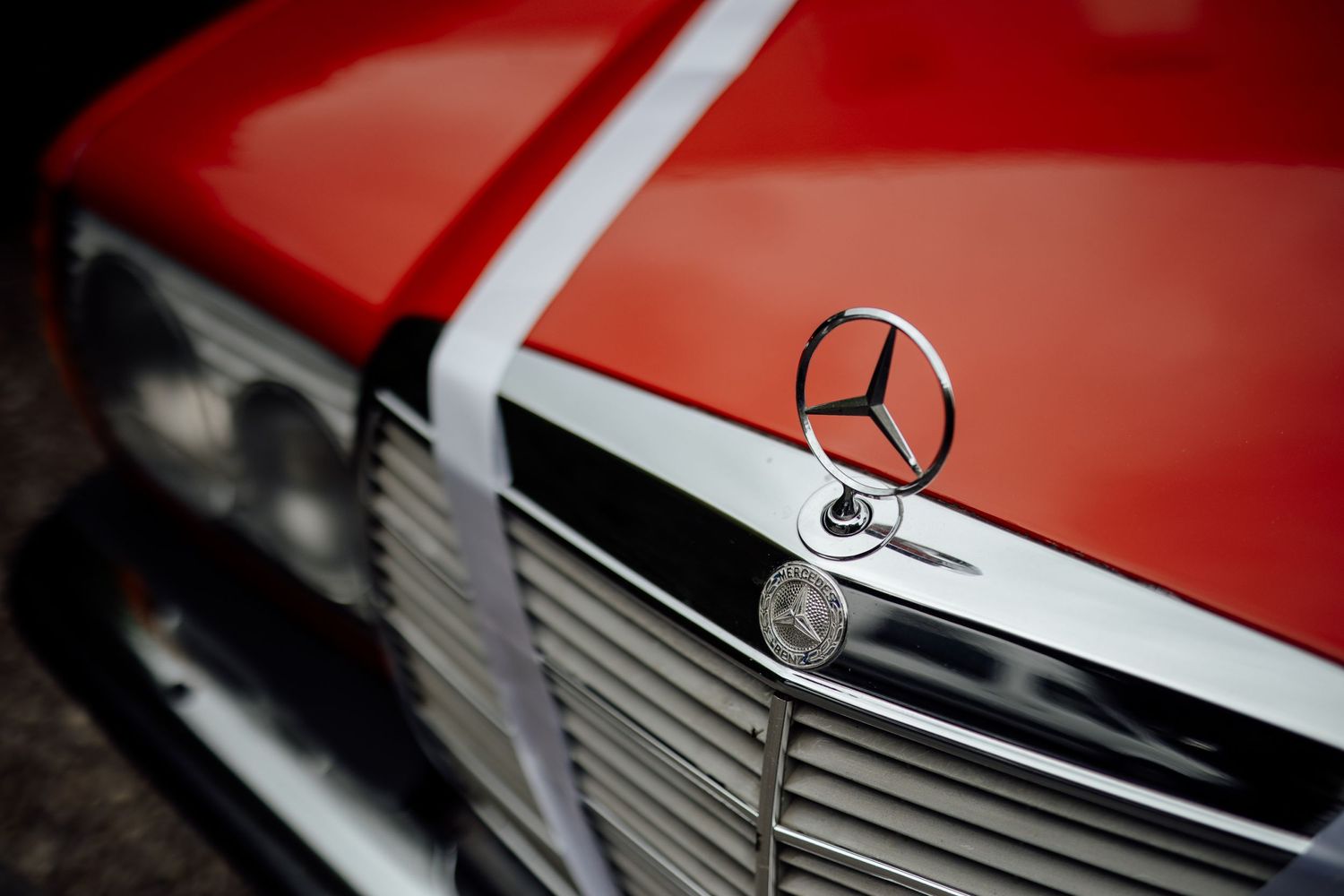 Close-up detail of classic red Mercedes-Benz hood ornament and grille.