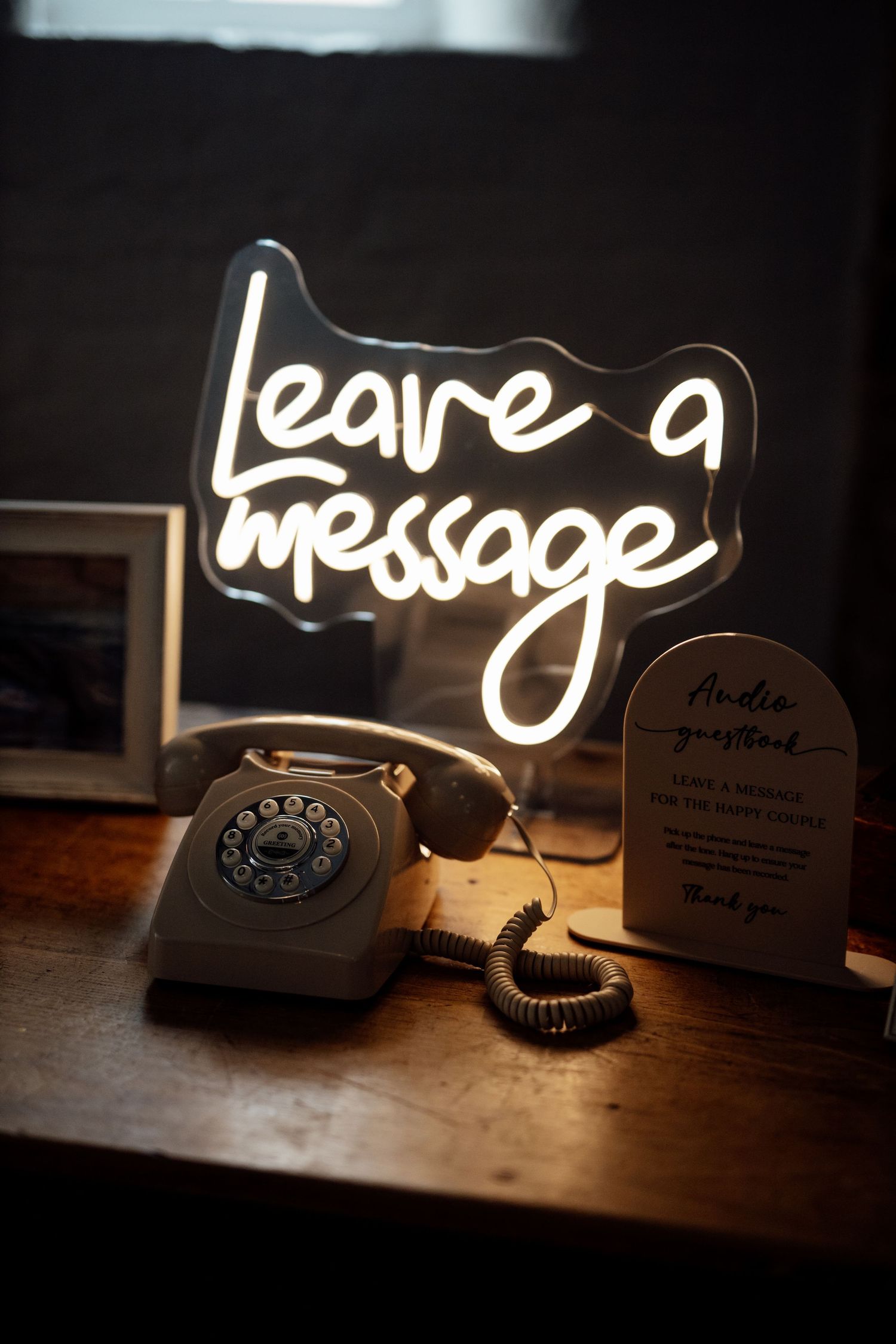Decorative neon signs displaying 'Leave a message' with vintage telephones on wooden surface.