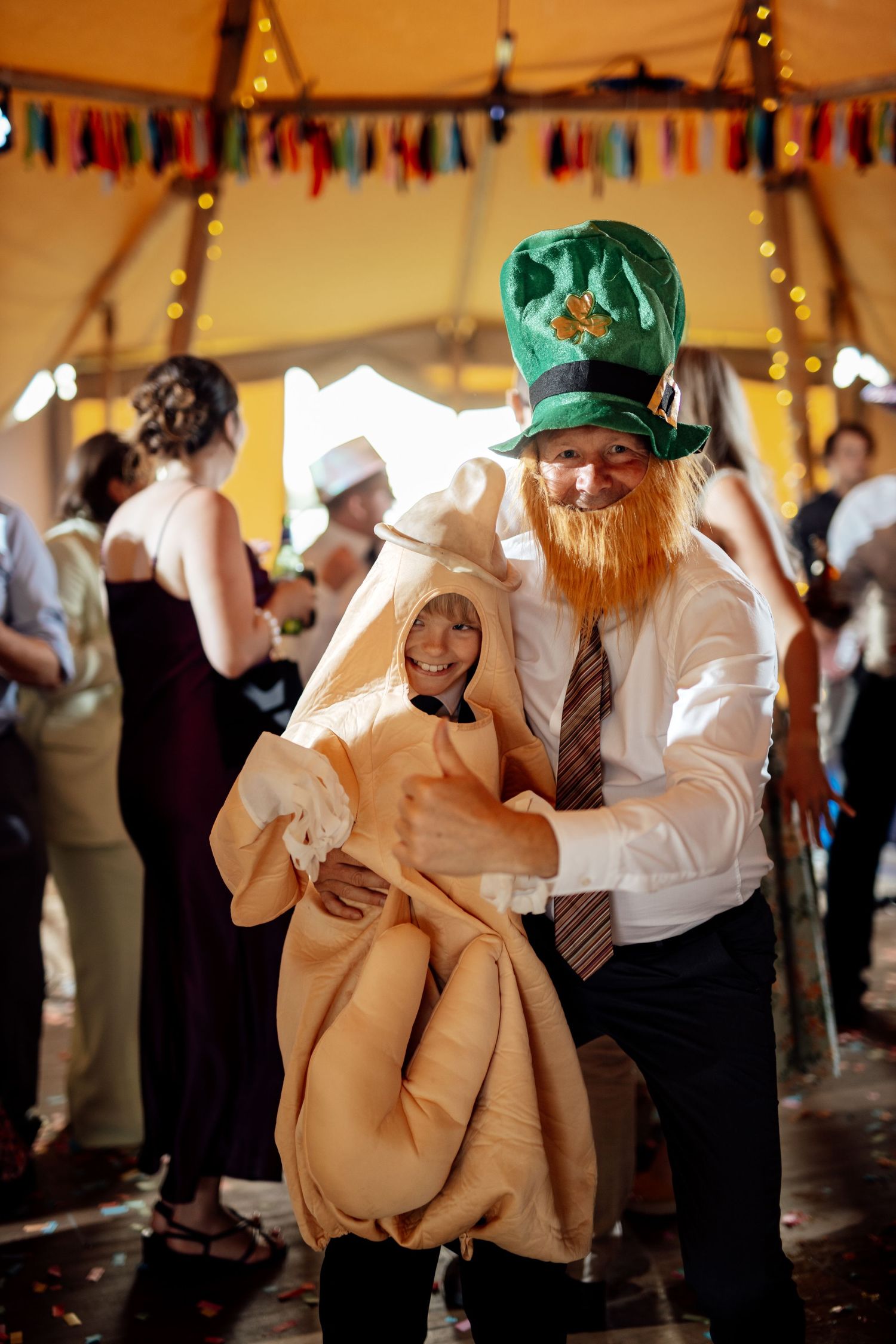 Person in festive green hat and tie dancing with prop at party under colorful bunting.