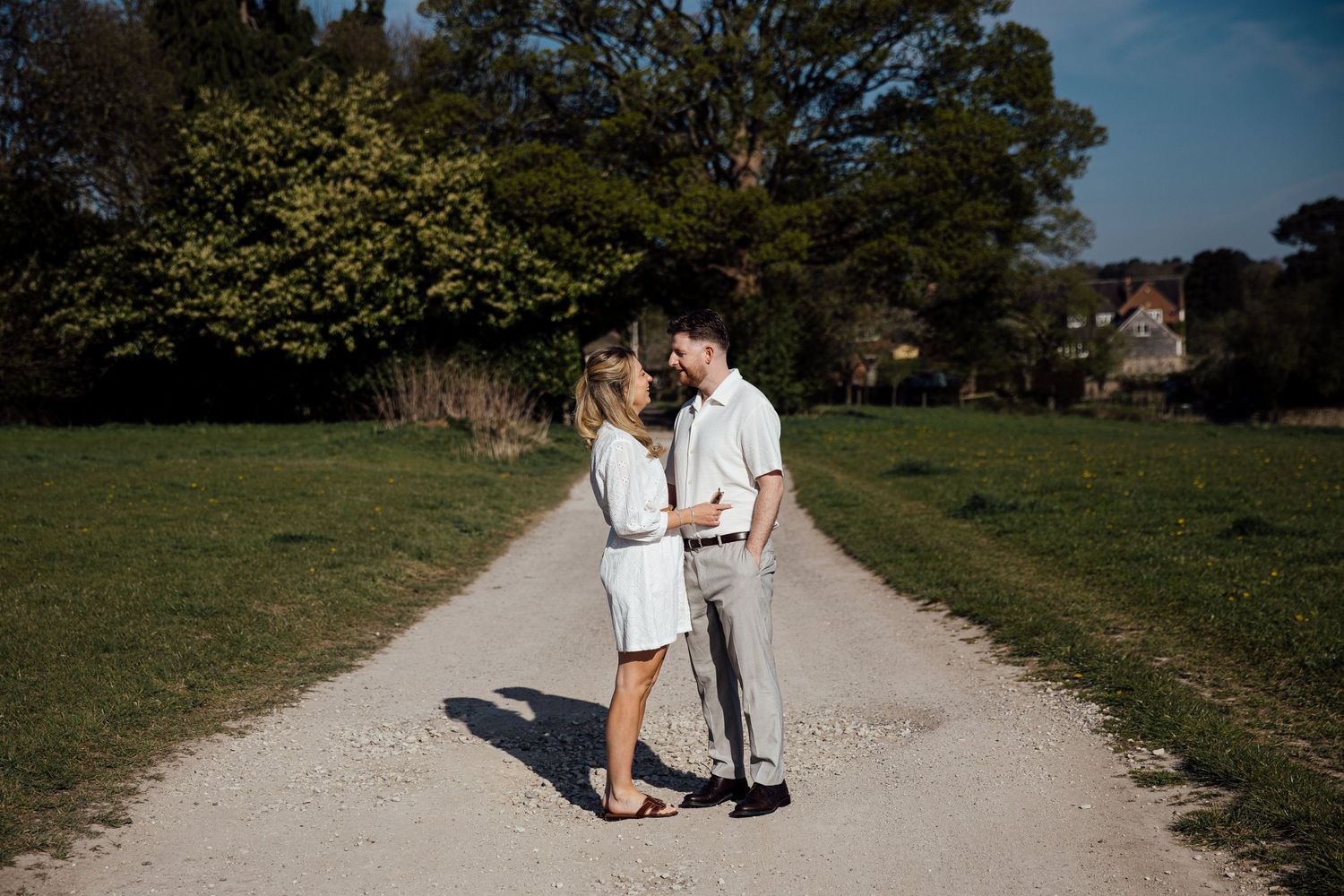 A couple walks along a winding dirt path through a scenic rural landscape.