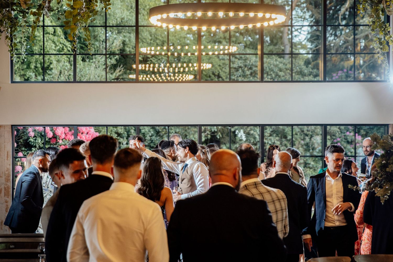 Modern wedding reception venue with string lights and large windows overlooking greenery.