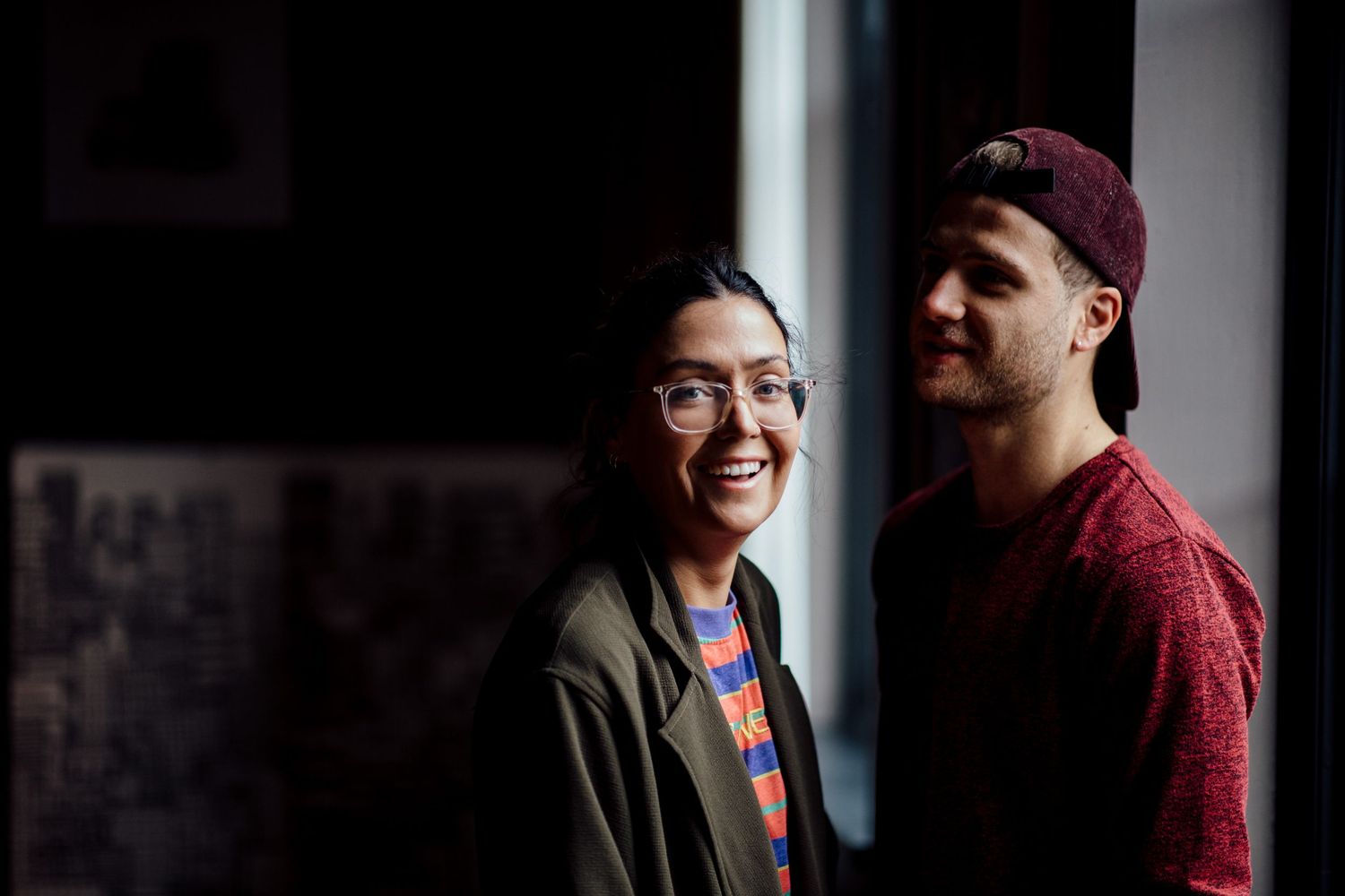 A couple shares a candid moment together against a dark background.