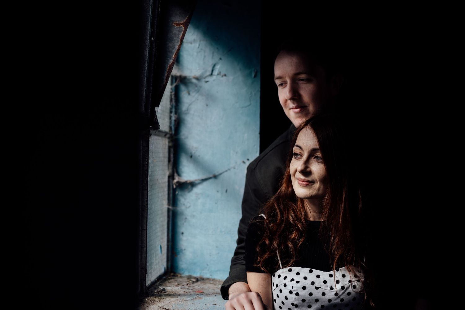 Indoor portrait session with dramatic lighting against a textured wall background.
