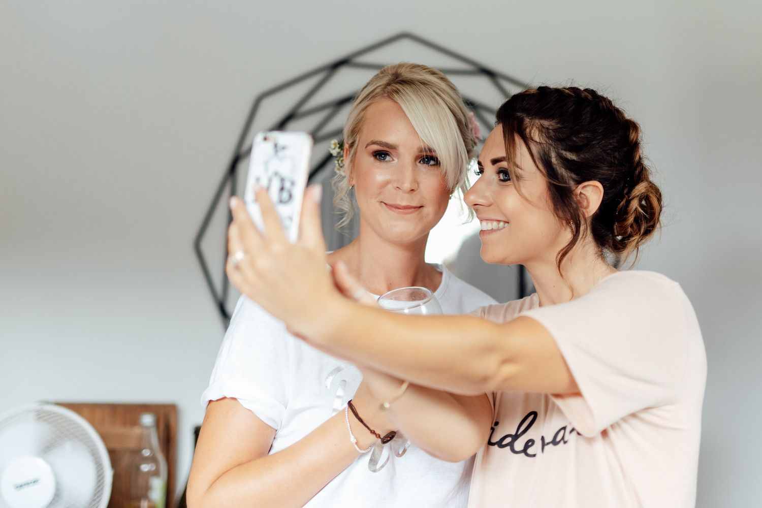 Two women in casual attire taking a selfie together while smiling.