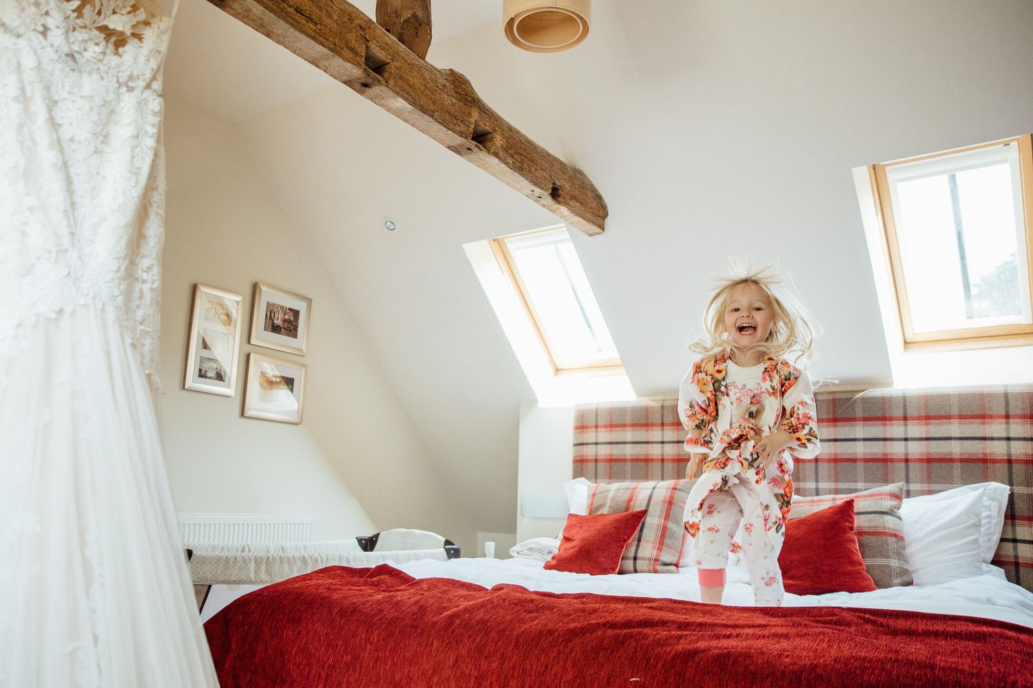 Bright attic bedroom with red bedding and exposed wooden beams.