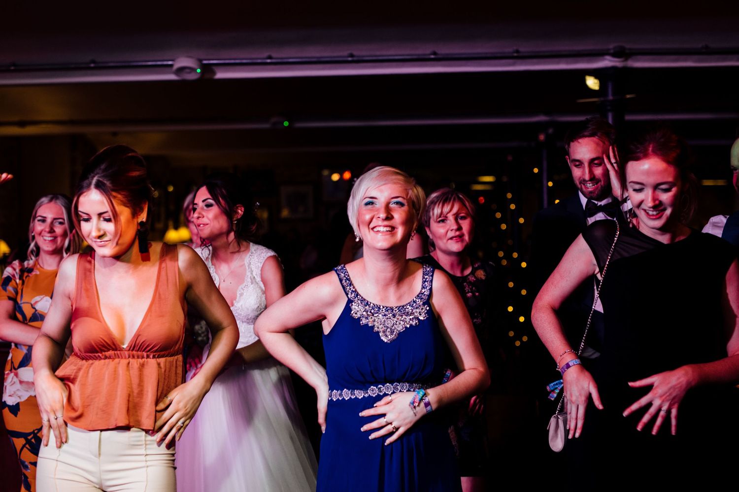 Silhouettes of wedding guests dancing and celebrating in a dark venue.