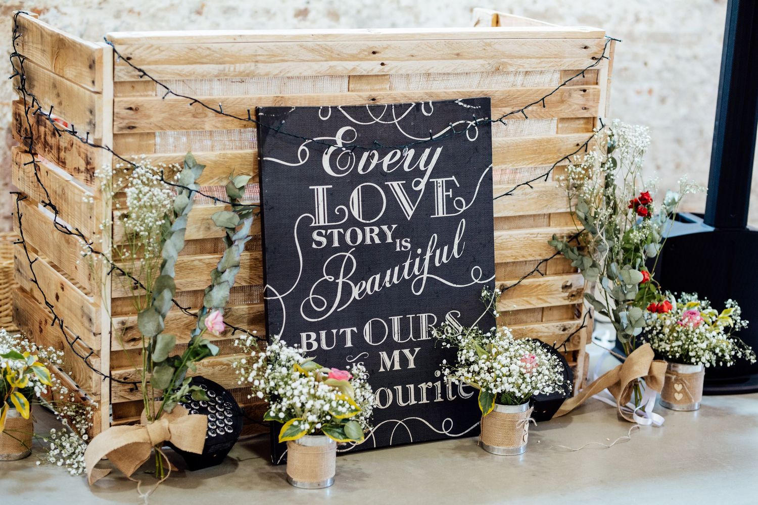 Rustic wedding decor with chalkboard signs and floral arrangements against a wooden backdrop.