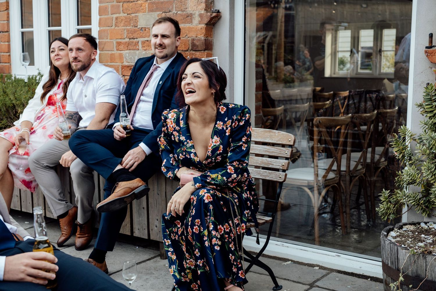 Wedding guests socialize and celebrate outside a rustic brick building.