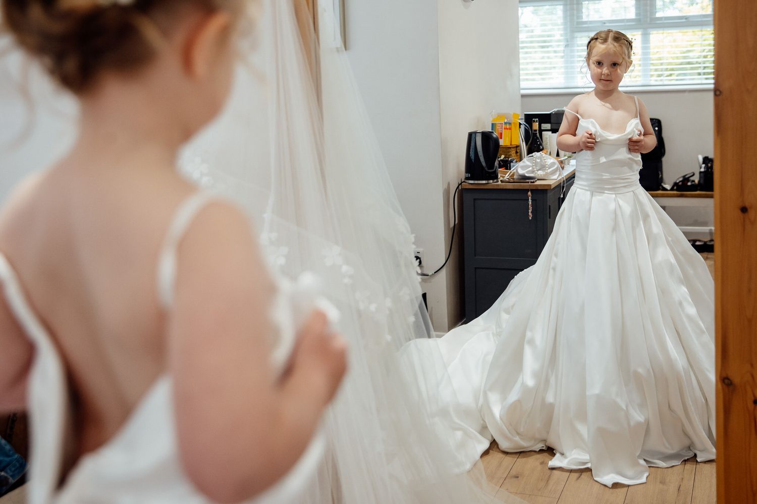 Elegant white wedding dress with flowing train captured in natural window light.
