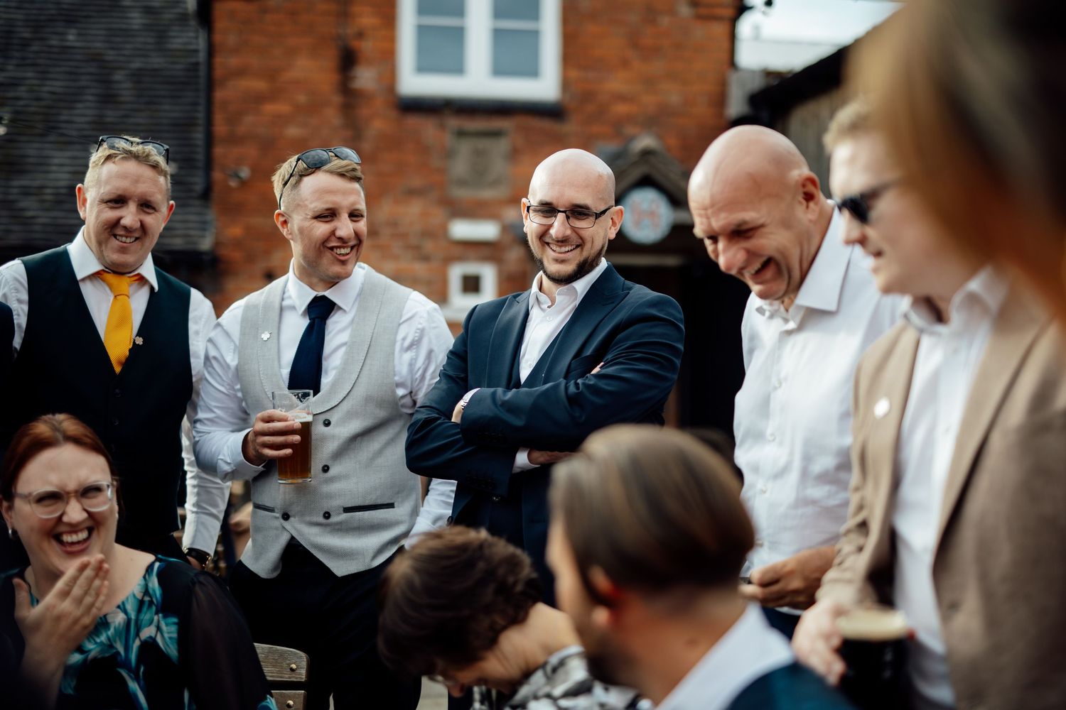 Wedding guests laugh and share stories during a lively outdoor cocktail reception.