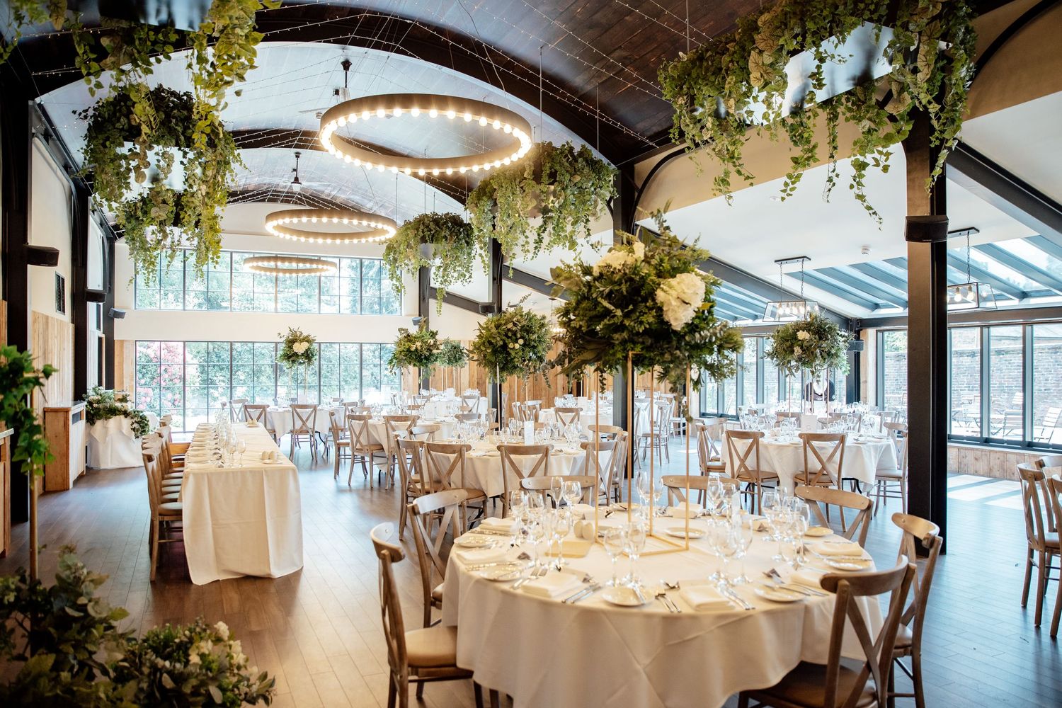 Elegant wedding reception venue with hanging greenery and crystal chandeliers.