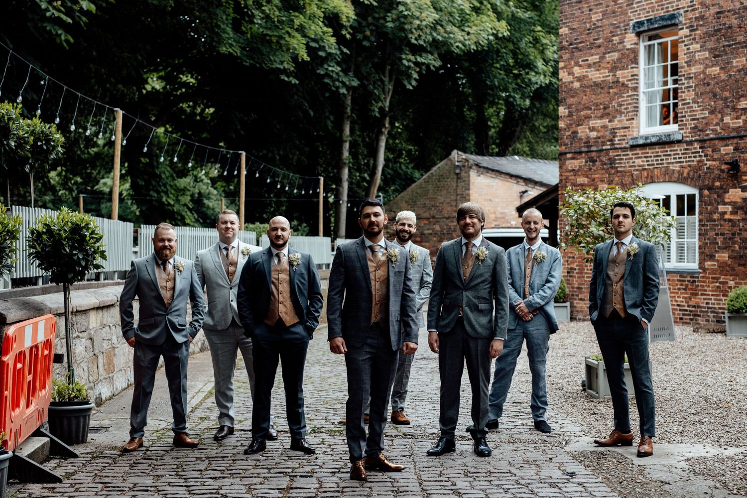 Wedding party posing for formal photos in front of a classic brick building.