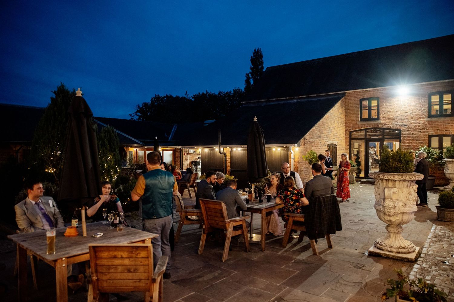 Evening outdoor wedding reception with string lights and guests mingling.