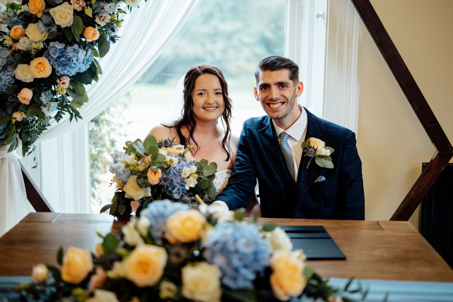 Beautiful wedding floral arrangement with blue hydrangeas and yellow roses frames a special moment.