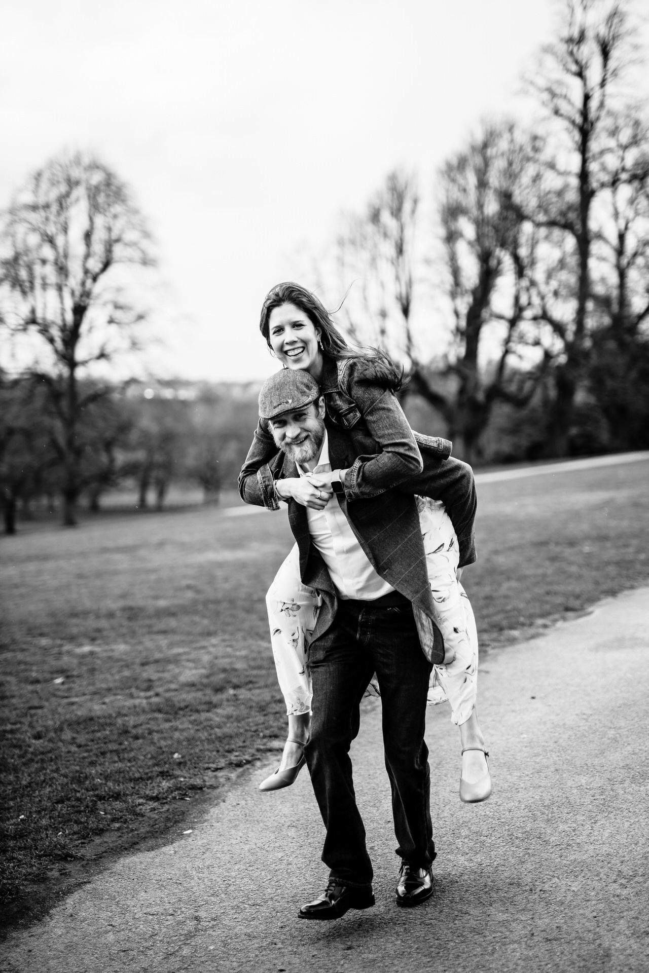 A playful couple shares lighthearted moments on a park pathway.