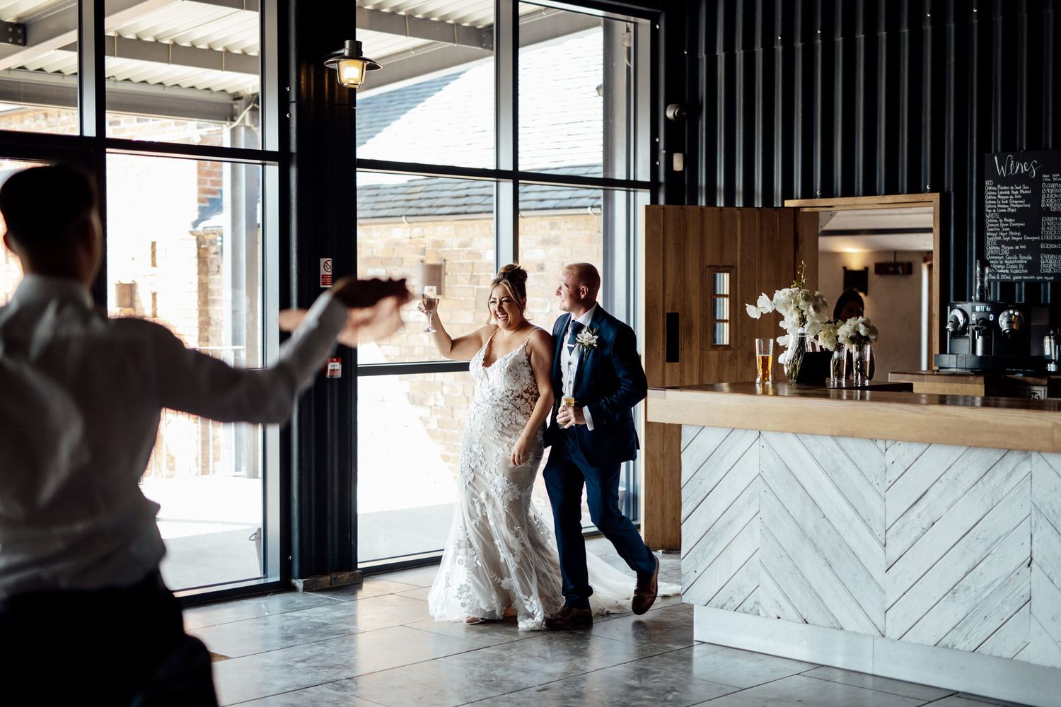 Modern wedding venue interior featuring geometric white bar and glass windows.