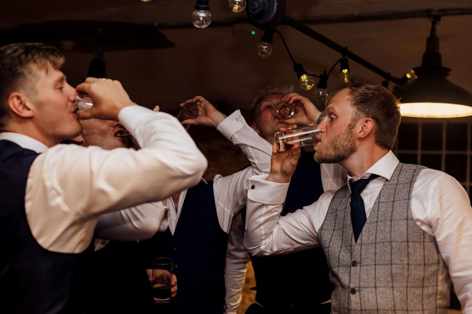 Groomsmen share celebratory drinks and toasts at a wedding reception.